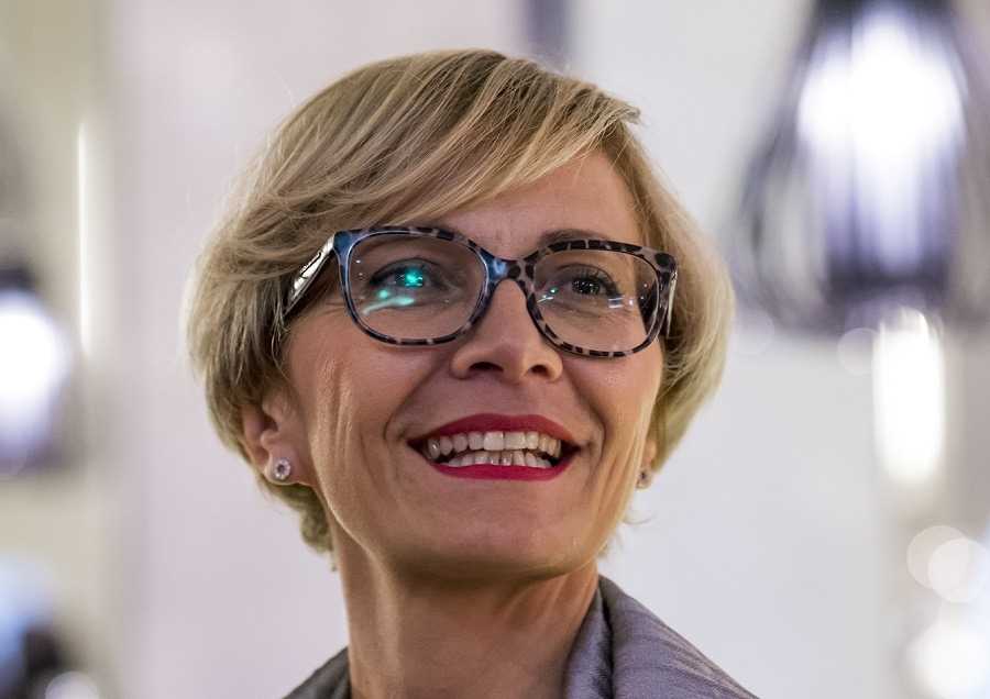 A woman wearing glasses and smiling at the camera